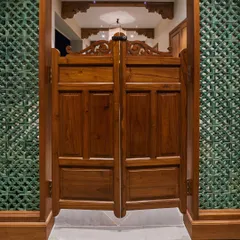 Inspired by my travels in Morocco, these wooden salon doors create a distinctive demarcation for a passage area. Paired with green ceramic *jali* on the sides, they allow for ventilation and create a beautiful play of shadows, bringing a touch of Moroccan style into the home.