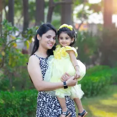 A mother holds her daughter, both dressed in cheerful yellow, sharing a beautiful smile for the camera. A perfect portrait of mother-daughter love in the golden light of the park.