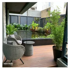A raised wooden deck provides a serene seating area overlooking a custom-built koi pond. This design elevates the viewing experience, making it feel as though you are floating just above the water's surface.