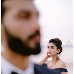 A creative portrait with a focus on her, her gaze thoughtful and serene. He is a soft presence in the foreground, a beautiful composition that tells a story of quiet admiration.