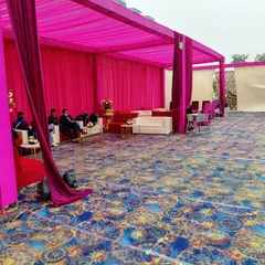 A dedicated lounge area inside a tent, featuring white sofas and center tables set against a vibrant pink backdrop.