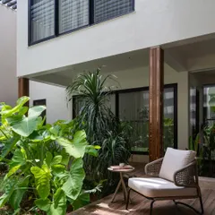 A quiet corner of the covered verandah, demonstrating our tropical modernism approach. This space provides a sheltered outdoor seating area that feels both part of the garden and an extension of the home's interior.