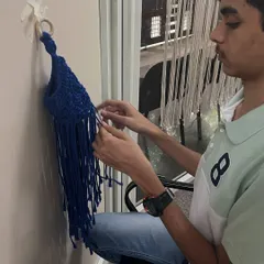 A student works on his blue macrame wall hanging. It's so rewarding to see a piece take shape knot by knot.