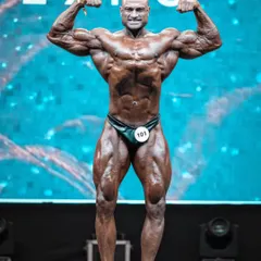 The iconic Front Double Biceps pose on the pro-qualifier stage. This shot captures the symmetry, muscle fullness, and conditioning that I strive for and teach.