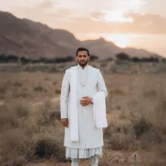 A solo portrait of Malay looking out at the horizon during his destination pre-wedding shoot. The soft, warm light of the setting sun creates a calm and majestic mood.