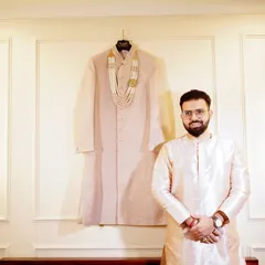 A classic groom's portrait. He stands proudly next to his wedding sherwani, a great shot to capture the anticipation before the ceremony.