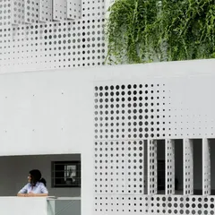 A detail of the LUCID House facade, where the perforated metal screen provides a veil of privacy for the inhabitants. This design element is both functional and aesthetic, giving the building a unique, light-weight identity.