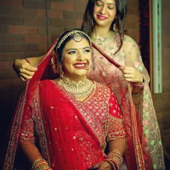 A heartwarming candid moment as a bride gets help with her dupatta. These unposed, genuine interactions are some of the most precious memories from a wedding day.