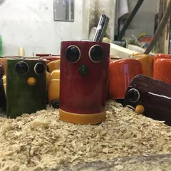 A closer look at our owl pen holders, nestled in a pile of wood shavings. This view highlights the glossy lacquer finish, which is achieved using a unique friction polishing method with pandanus leaves.