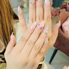 A dazzling set of long stiletto nails perfect for a bride or special occasion. It combines a soft pink glitter base with intricate silver rhinestone patterns and delicate 3D pink flowers.