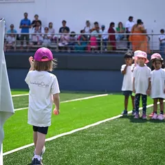 A student leads her team, holding the school flag at the start of the sports meet.