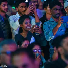 A young woman in the audience, capturing a memory at the Bengaluru Ganesh Utsava. In this digital age, it's amazing to see how music becomes a shared experience online and offline.