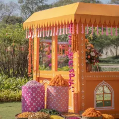 A traditional flower stall, or 'phoolon ki theli', decorated in bright orange and filled with baskets of marigolds and other flowers for the Haldi ceremony.