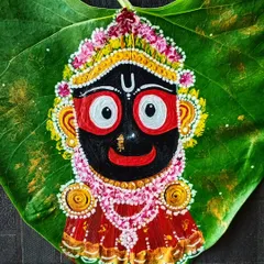 The finished Lord Jagannath painting on a Pipal leaf, shown against a dark, textured background. The vibrant colors of his attire and the intricate details of his crown stand out beautifully against the natural green leaf.
