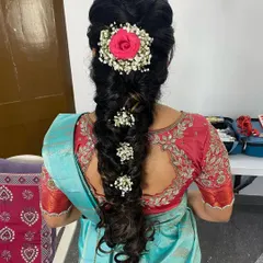 A beautiful messy braid for an engagement, adorned with a rose and baby's breath. This romantic and textured hairstyle is a popular choice for modern brides.