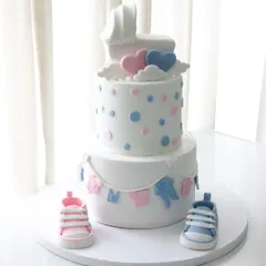 A full view of the baby shower cake, showing the tiny clothesline, baby carriage topper, and cute fondant baby shoes.
