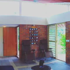I believe in using locally available materials to create authentic spaces. This living area features exposed wire-cut brick walls and large windows, flooding the room with natural light and creating a rustic yet contemporary home environment that feels connected to its surroundings.