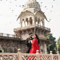 A vibrant and joyful shot in Jaipur. The bride's bright red saree pops against the classic architecture, while the birds in flight add a sense of life and movement to this beautiful pre-wedding photograph.
