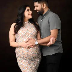 An elegant and intimate couple's portrait. The focus here is on the connection between the parents-to-be, captured with classic lighting against a rich, dark backdrop for a timeless feel.