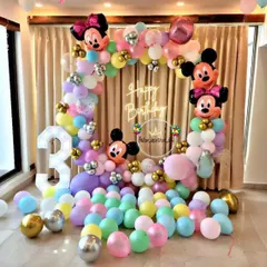 A colorful Mickey and Minnie Mouse theme for a third birthday. The setup includes a pastel balloon arch with character heads, a "Happy Birthday" neon sign, and a large light-up number '3'.