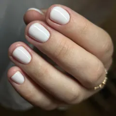 A crisp, clean white manicure on short, natural nails. The flawless application and high-gloss finish demonstrate the precision of our Russian manicure service.