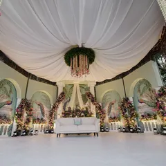 A stunning reception stage with a pastel-painted backdrop of peacocks and florals, blending artistry with natural beauty.