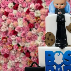 This close-up of a three-tiered Boss Baby cake highlights the detailed fondant work, from the tiny cookies to the formal suit design, making it a truly impressive celebration cake.