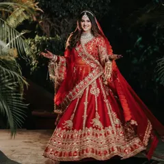 A full-length shot of the bride, capturing the magnificent flare of her red lehenga. The movement and her joyful expression make this a dynamic and beautiful portrait, showcasing her entire bridal look.