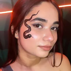 A detailed, glittering black snake design that curves along the face. This shows how I can create custom, artistic face paint that complements your look and stands out.