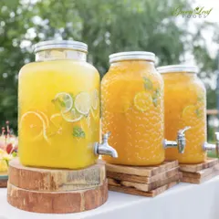 For outdoor events, refreshing drinks are a must. We set up these beautiful glass beverage dispensers filled with fresh orange and lemon-lime juice, allowing guests to help themselves to a cool drink.