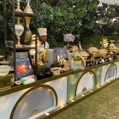 This is a section of one of our outdoor buffet setups, featuring a live Teppanyaki grill. The counter is decorated with ornate vases and our custom-branded signage, ensuring a cohesive and premium look.