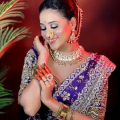 The complete bridal ensemble. This photo highlights the harmony between the makeup, hairstyle, jewelry, and the intricate purple saree.