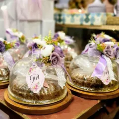 Announcing a new arrival is such a joyous occasion, and we love creating the perfect favors to share the news. These "It's a Girl" announcement gifts feature individual cakes under glass cloches, each adorned with delicate purple flowers, lace ribbons, and a personalized floral tag. It's a sweet and elegant way to celebrate your new bundle of joy.