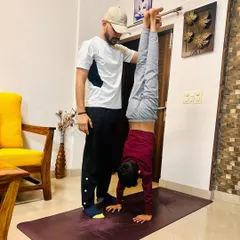 Inverting the ordinary. Assisting a young student with a handstand, focusing on building shoulder strength and core engagement for a stable and controlled pose.