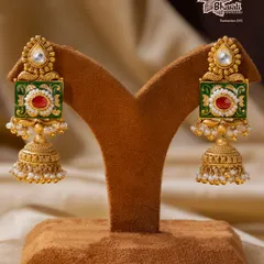 A tribute to India’s timeless artistry. These Meenakari jhumka earrings are hand-enameled with vibrant green and red floral motifs, framed in antique gold. The design is completed with a classic bell shape and delicate pearls.
