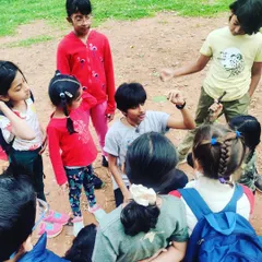 An older child shares his knowledge about a leaf he has found, teaching the younger children in a beautiful moment of peer-to-peer learning during our park visit.