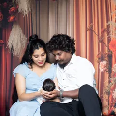 A tender moment as new parents gaze down at their newborn, cupping the baby's head in their hands.
