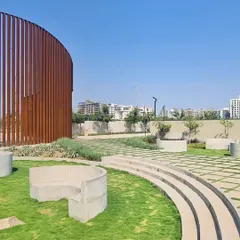A landscaped park in our Raipur project, where curved concrete seating and stepped lawns follow the lines of the Corten steel screen, creating a cohesive and sculptural public space.