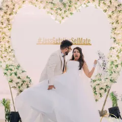 A fun and candid moment of the couple at their beach wedding reception, in front of a beautiful heart-shaped floral arch.