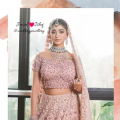 A full-length shot of a bride in a gorgeous off-shoulder pastel lehenga. The look is completed with a layered diamond and emerald necklace set for a touch of modern glamour.