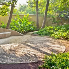 A detail from our Dumas House project, showing how we blend hardscape and softscape. The custom-patterned walkway flows organically into a seating area, surrounded by lush tropical foliage to create a tranquil and artistic garden path.