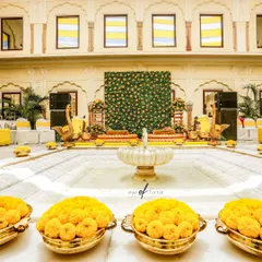 The grand Haldi decor setup in a palace courtyard. The vibrant yellow marigolds and traditional elements create a festive and royal atmosphere.