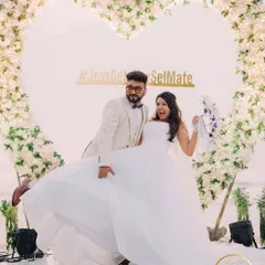 The couple strikes a pose at their beachside celebration, perfectly framed by the floral heart.