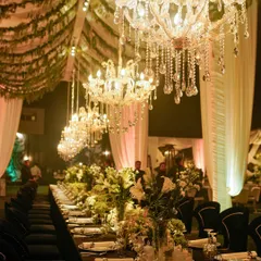 A long shot of the banquet dining setup, showing the dramatic effect of the row of crystal chandeliers hanging over the elegantly dressed table.