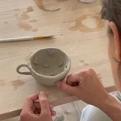 It all starts with a lump of clay and an idea. In our hand-building workshops, you can create something truly personal, like this mug being decorated with little hearts. It’s about making functional art that you can use every day.