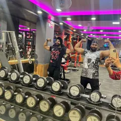 Hitting a double bicep pose with a friend in the gym. Surrounding yourself with people who share your drive is key to staying motivated.