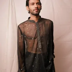 A relaxed yet stylish portrait showcasing a sheer black kurta. The simple white background and clean lighting put all the focus on the modern design of the garment and the model's confident presence.