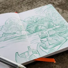 A close-up view of my sketchbook and the 4-in-1 ballpoint pen I used for this landscape drawing. You can see the cross-hatching and line work that create texture and depth in the trees and water.
