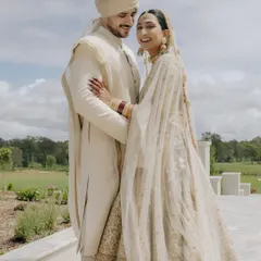 A joyful moment from a countryside wedding in Brisbane, Australia. The couple's coordinated Sabyasachi outfits look elegant against the open, natural landscape.