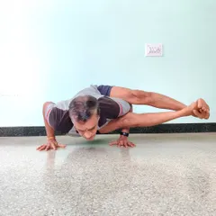 Astavakrasana (Eight-Angle Pose). An advanced arm balance that requires significant arm strength, core engagement, and hip flexibility. The body is supported entirely on the hands.